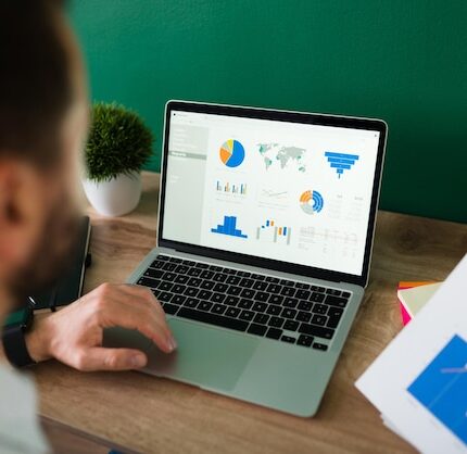 rear-view-young-man-working-his-laptop-looking-work-report-graphs_662251-2165