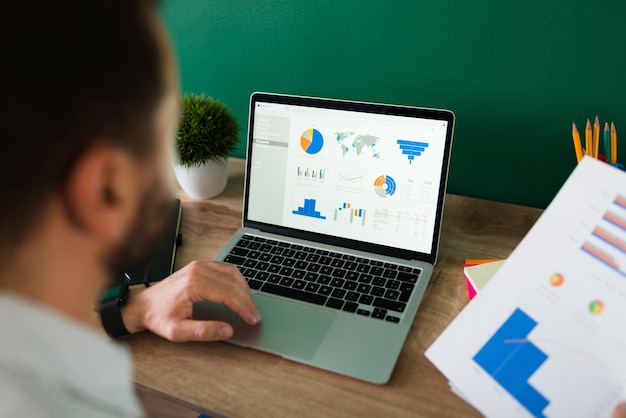 rear-view-young-man-working-his-laptop-looking-work-report-graphs_662251-2165